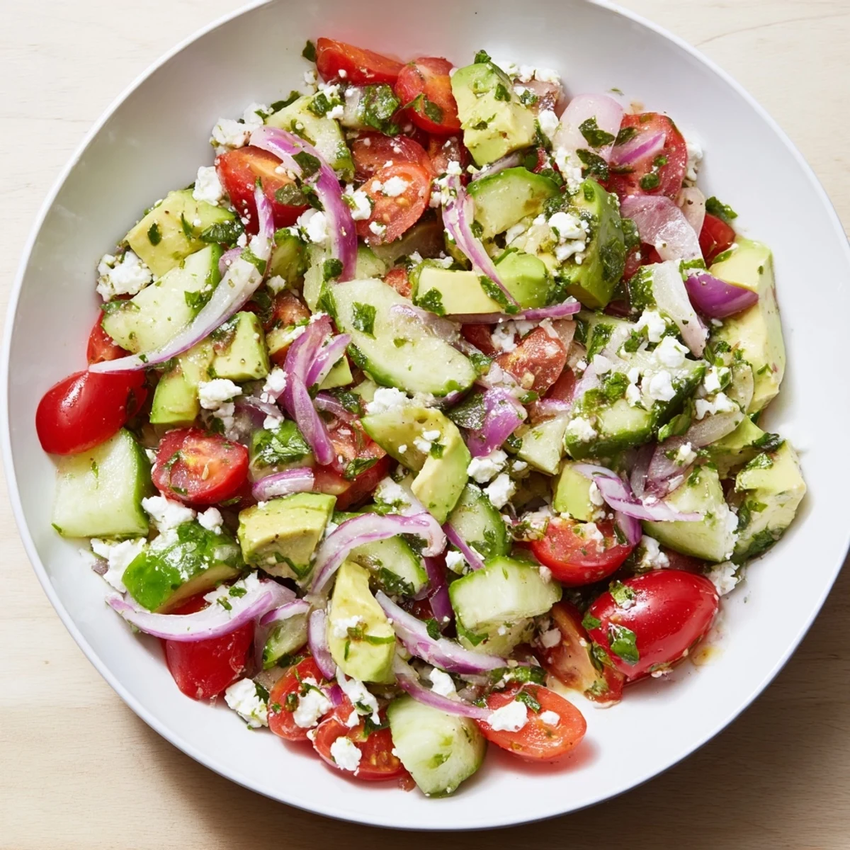 Crisp cucumber, juicy tomatoes, and creamy avocado in this Fresh Salad, garnished with crumbled feta.