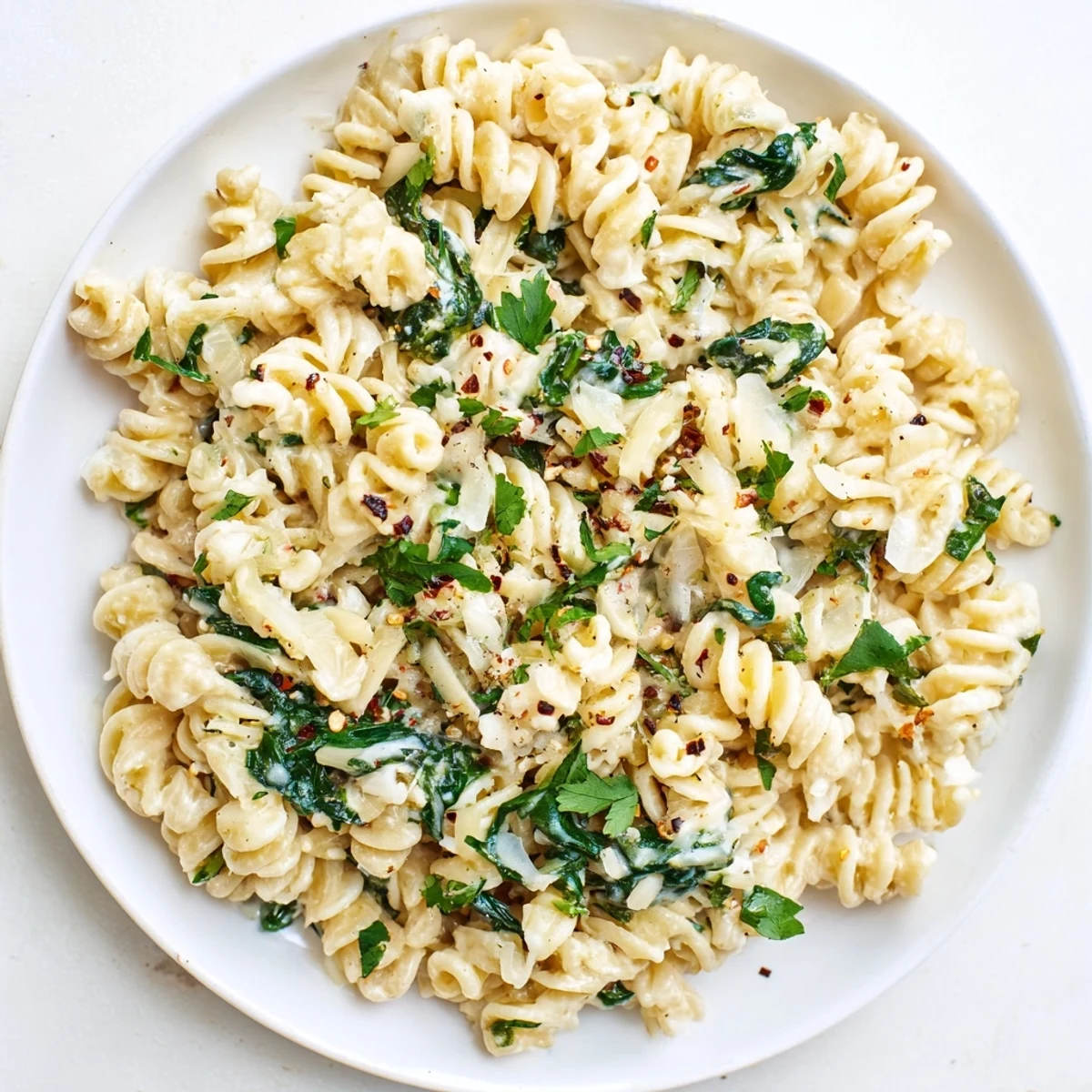A steaming bowl of Magic Casserole, pasta loaded with creamy cheese and fresh, vibrant spinach.