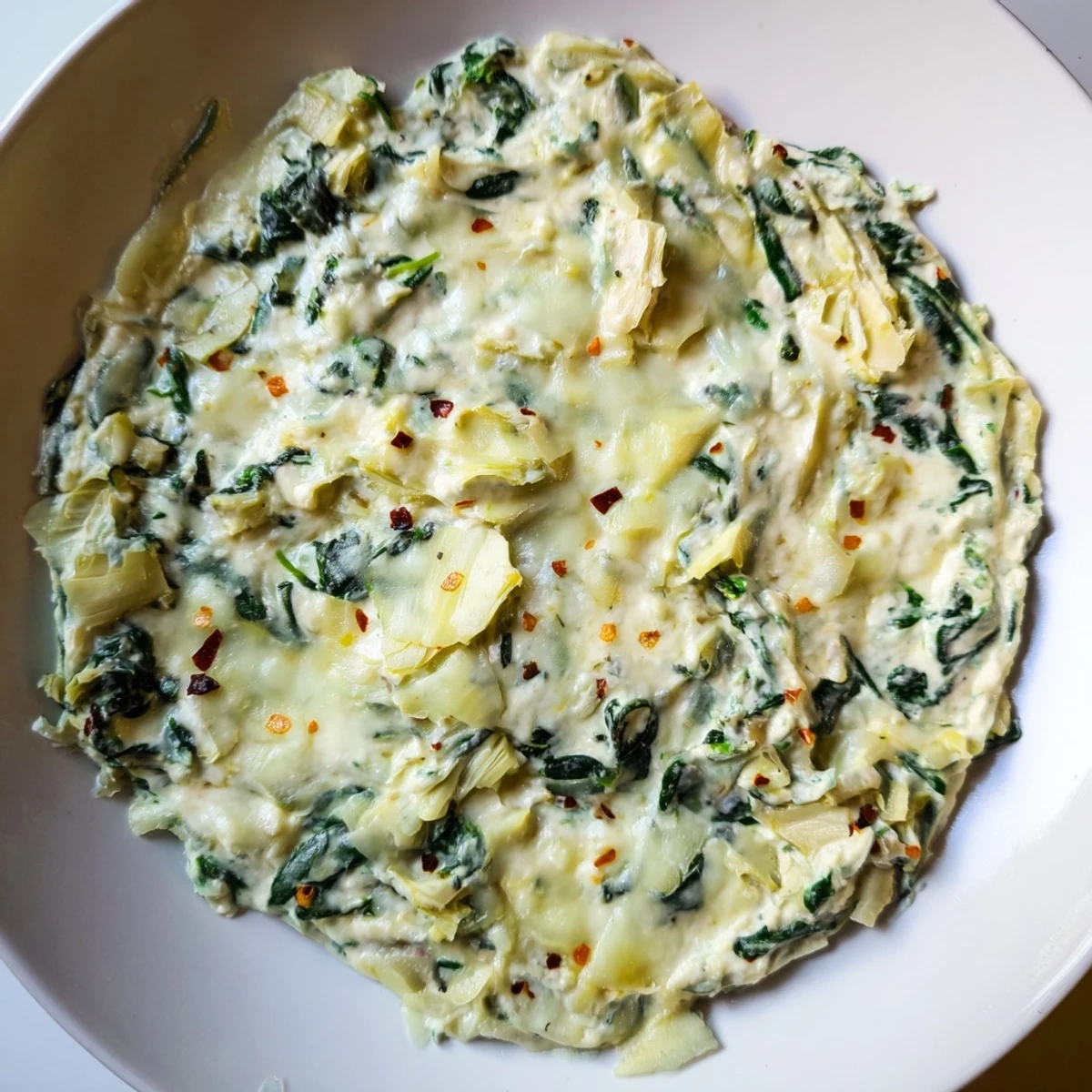 Close-up of inviting spinach artichoke dip, a favorite party appetizer ready to be scooped up.