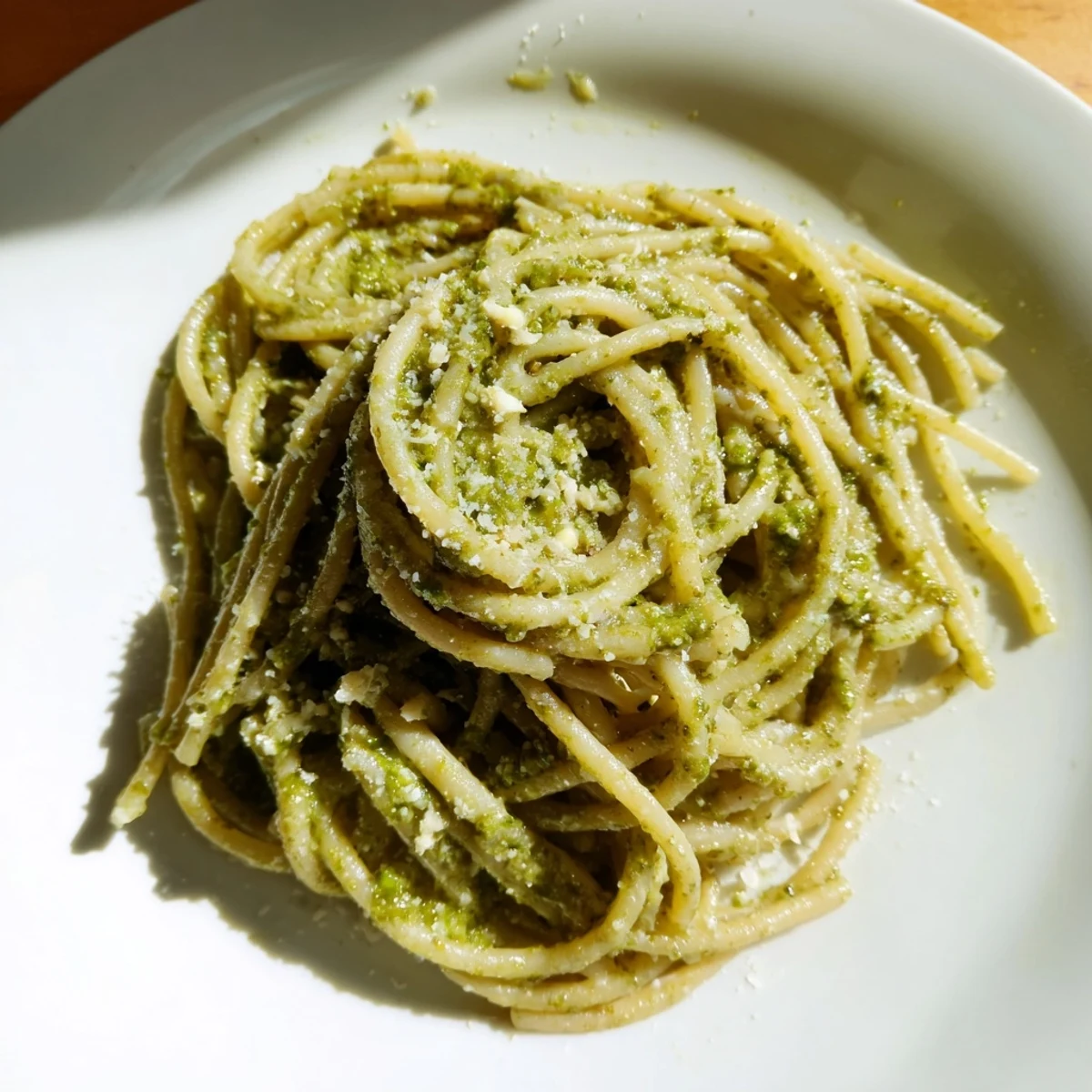 Steaming creamy sunflower seed pesto pasta swirls with vibrant green basil sauce and golden toasted seeds in a rustic white bowl.  