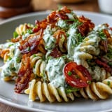 Creamy BLT pasta, showcasing crispy bacon, juicy tomatoes, and cool, fresh greens.