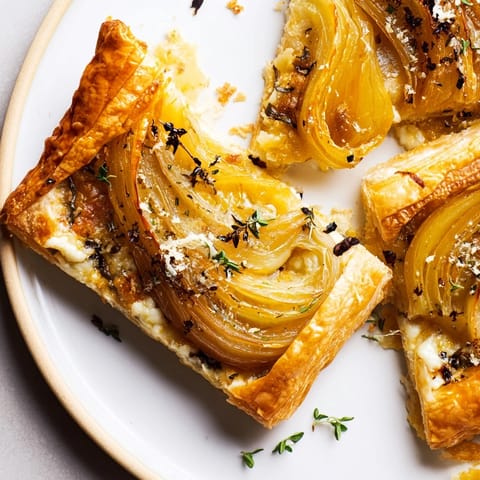 Warm, appetizing shot of a rustic Caramelized Onion Tart with melted Gruyère and fresh thyme.