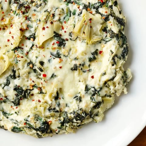 Warm, creamy spinach artichoke dip, fresh from the oven, with melting cheese and herbs.
