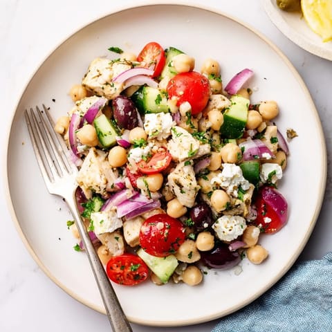 Fork-ready Mediterranean Chickpea Chicken Salad tossed with Kalamata olives and fresh parsley, drizzled in zesty lemon-oregano dressing for a healthy lunch.