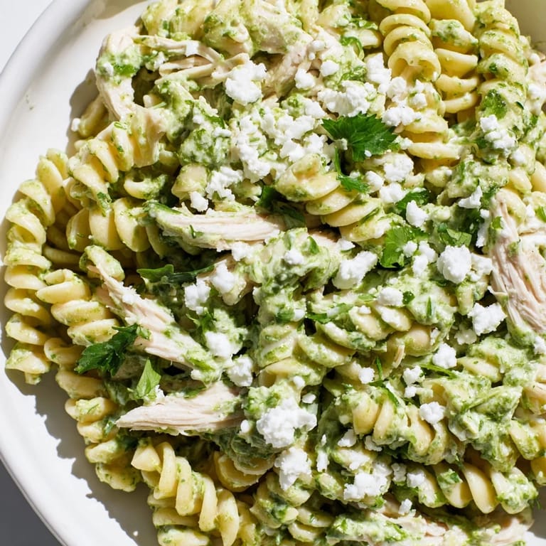 Tender rotini and shredded chicken coated in a bright green cilantro lime chicken pasta sauce, topped with crumbled feta and extra cilantro.