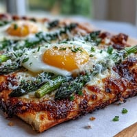 Crispy flatbread topped with roasted asparagus, a baked egg, and parmesan for a savory brunch dish.  